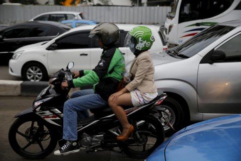 A Gojek driver pillions a customer as he rides his motorcycle through a business district street in Jakarta, June 9, 2015. (REUTERS/BEAWIHARTA)