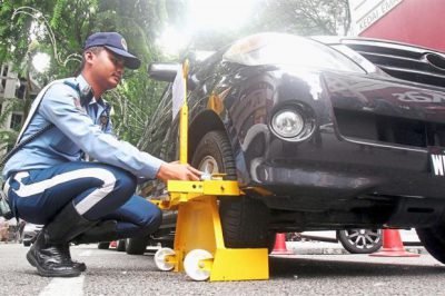 A DBKL enforcement officer clamping a car that had double parked. (Photo from The Star)