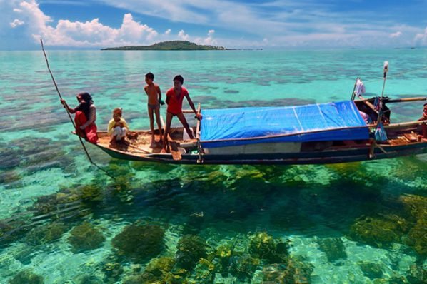 Local children on a raft in sparkling clear waters at Pulau Sipadan